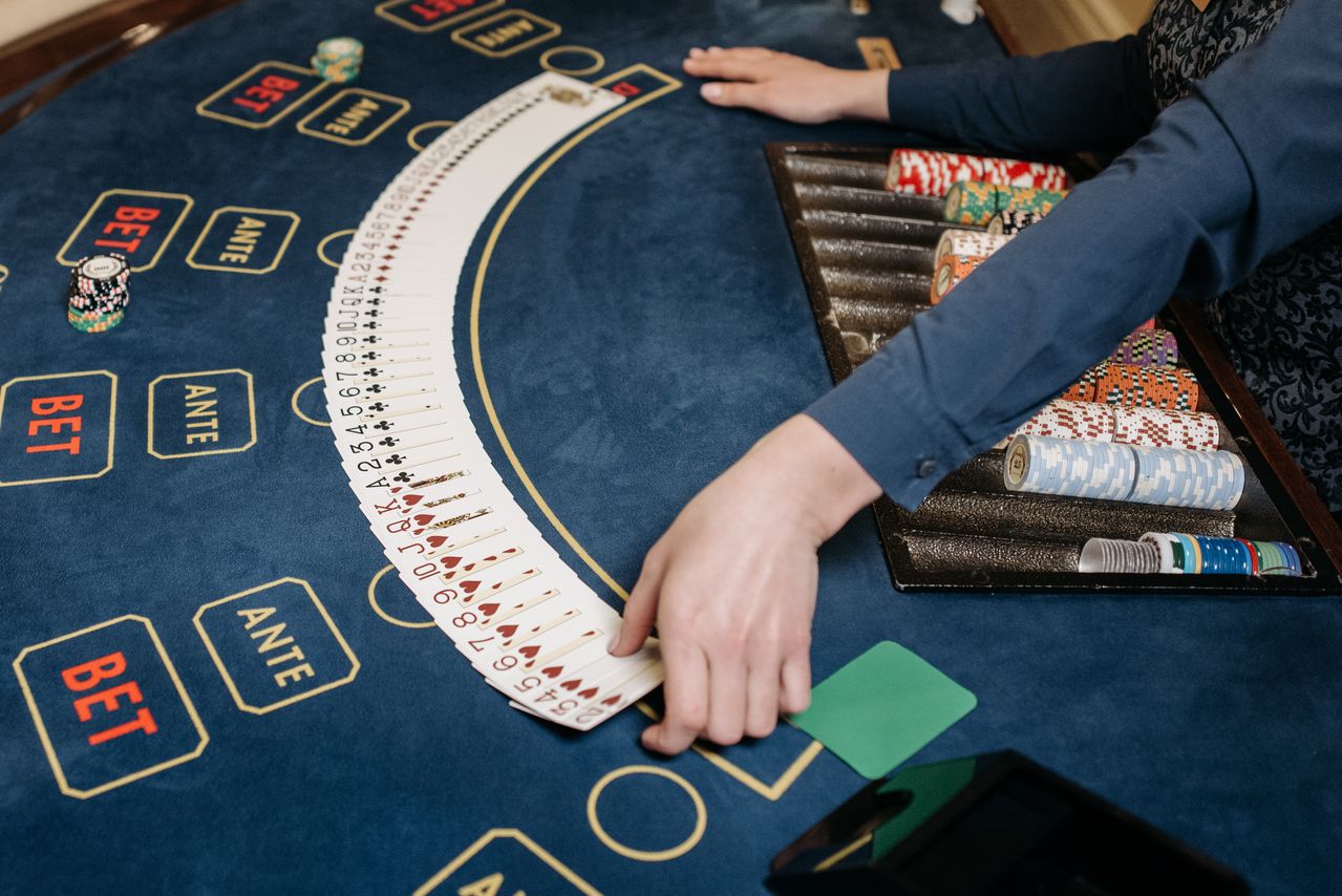 Dealer spreading cards across a midnight-blue casino table