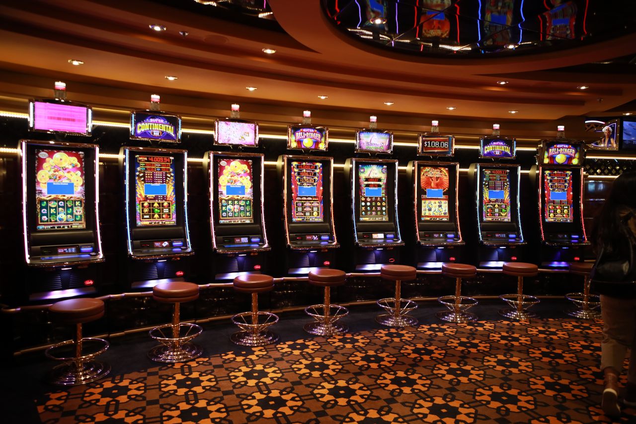 Row of gaming machines along a warmly lit casino wall