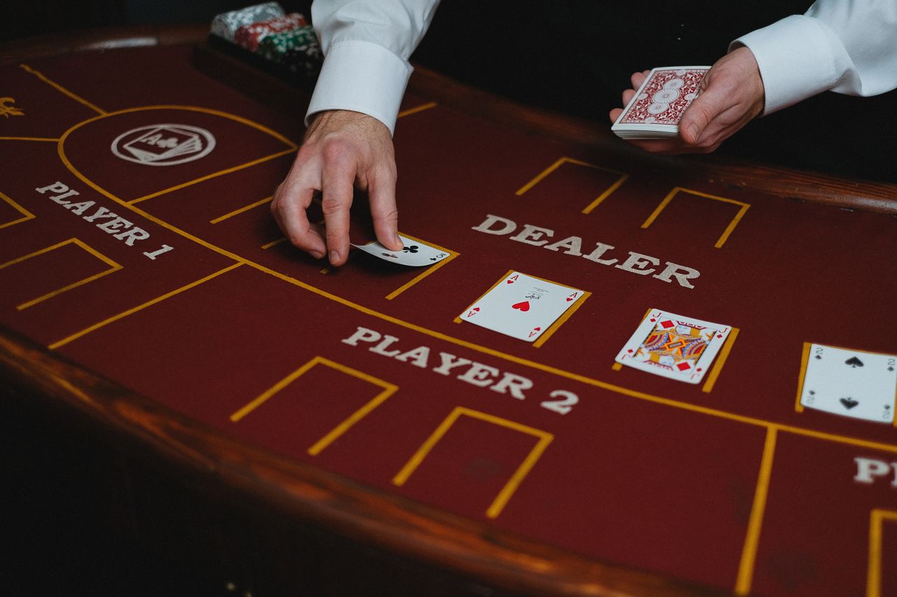 Dealer placing cards on a burgundy felt table in a quiet salon