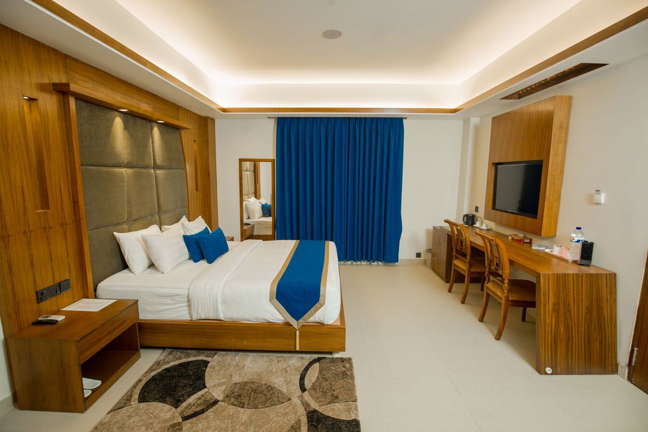 Hotellsoverom med blå draperier, skrivebord i tre og varmt taklys