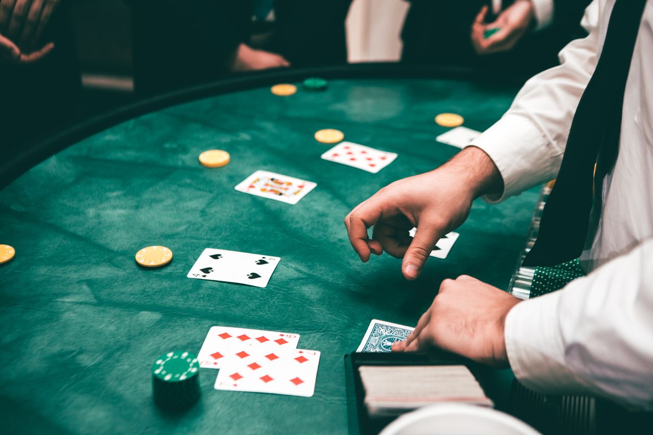 Dealer in formal attire handling cards on green felt